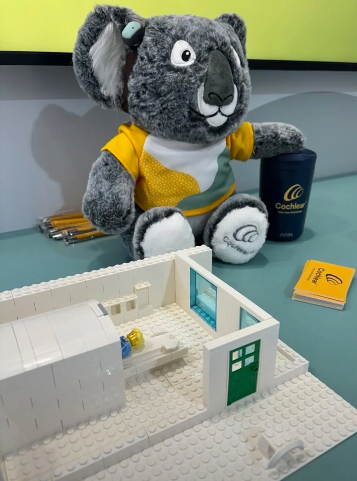 A plush toy, a toy building model and Cochlear booklets on a table in our office