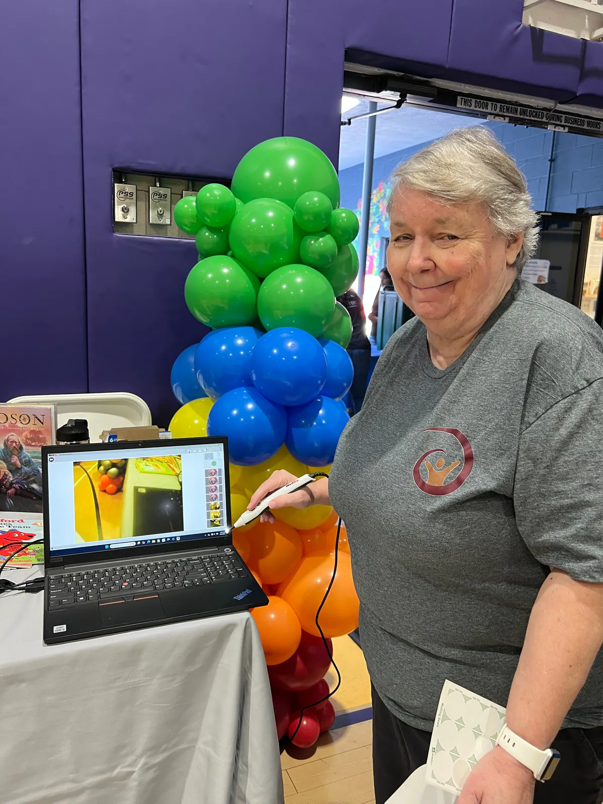 Dr. Mary Frintner at a community event beside a tower of colorful balloons